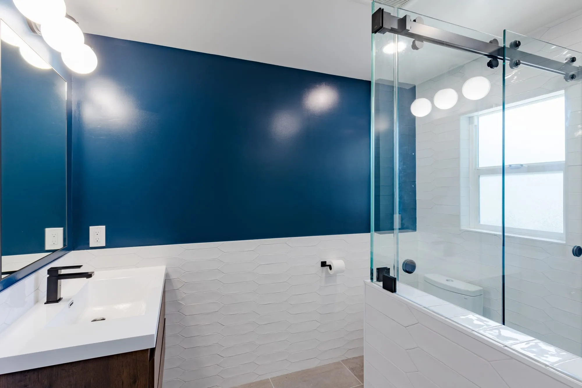 Vanity and mirror under a row of globe lights