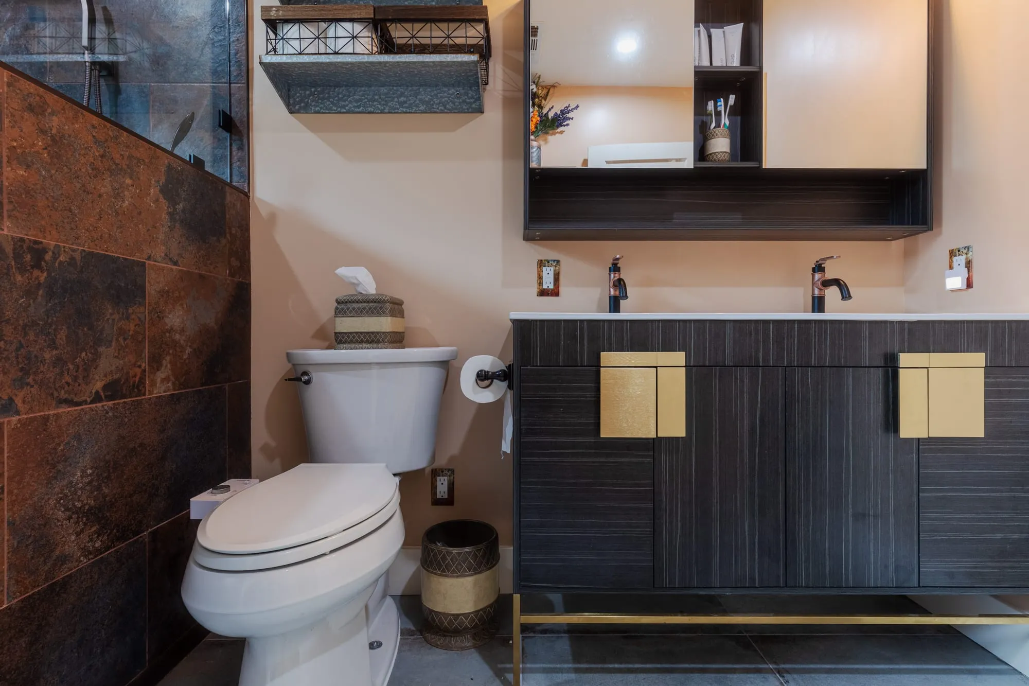 Vanity and slate-tone tile wall with a floating shelf above
