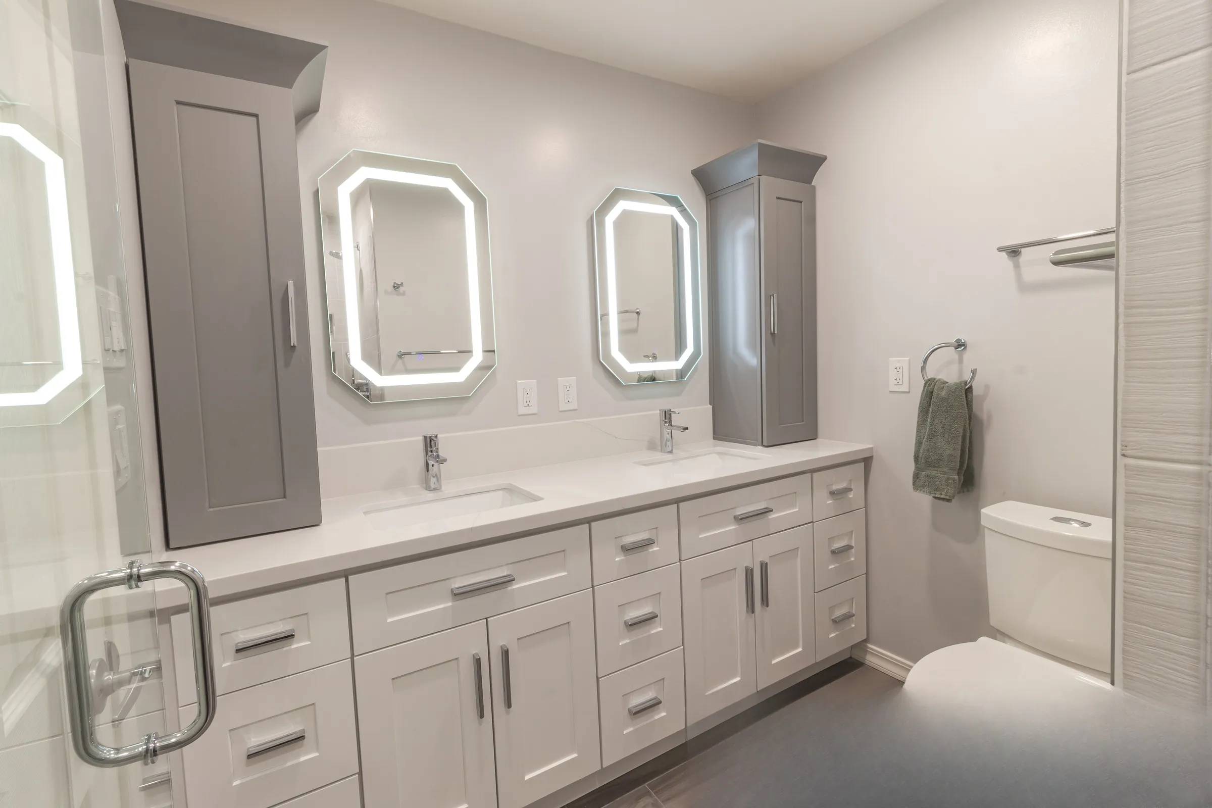 Full vanity run with shaker doors, chrome pulls and a grey linen tower at each end