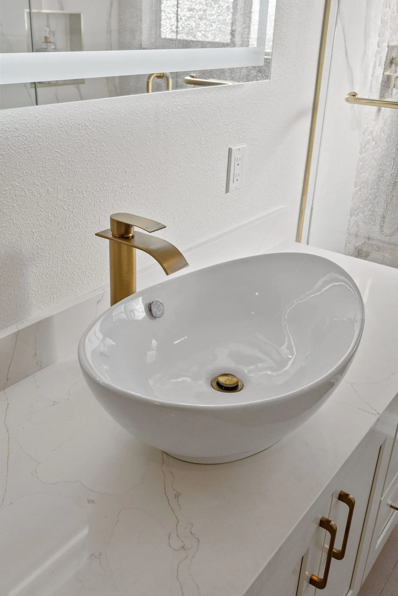 Close view of a rounded vessel basin with a tall brushed brass tap