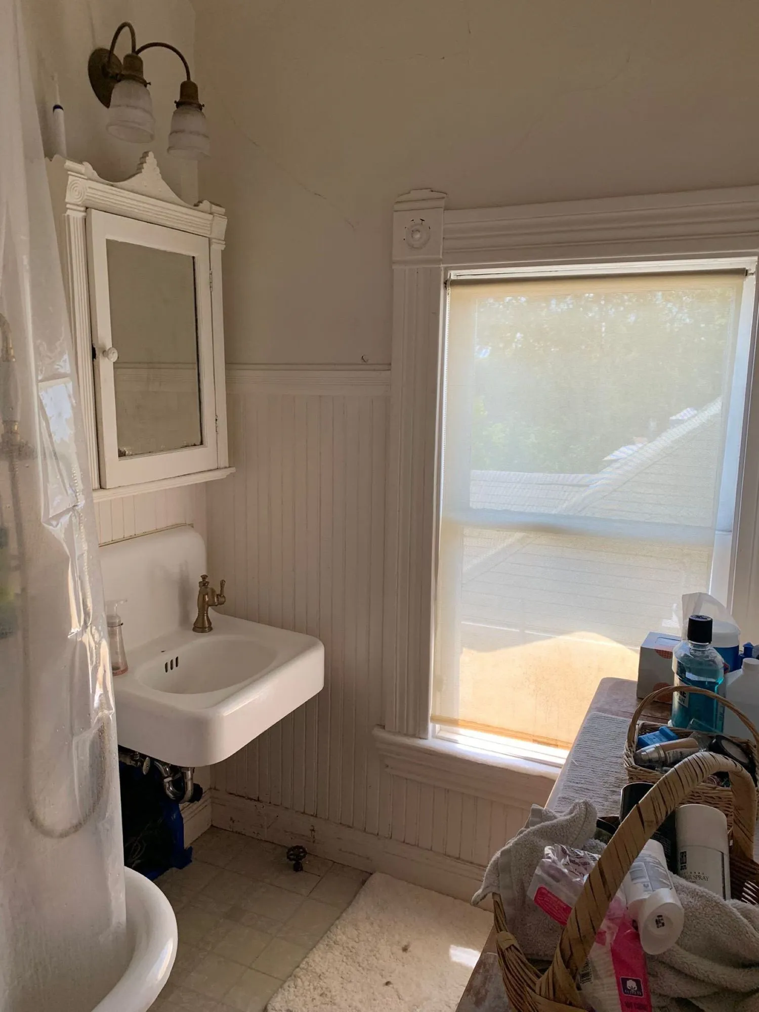 Original bathroom before remodel, wall-hung sink with beadboard wainscot and vintage medicine cabinet