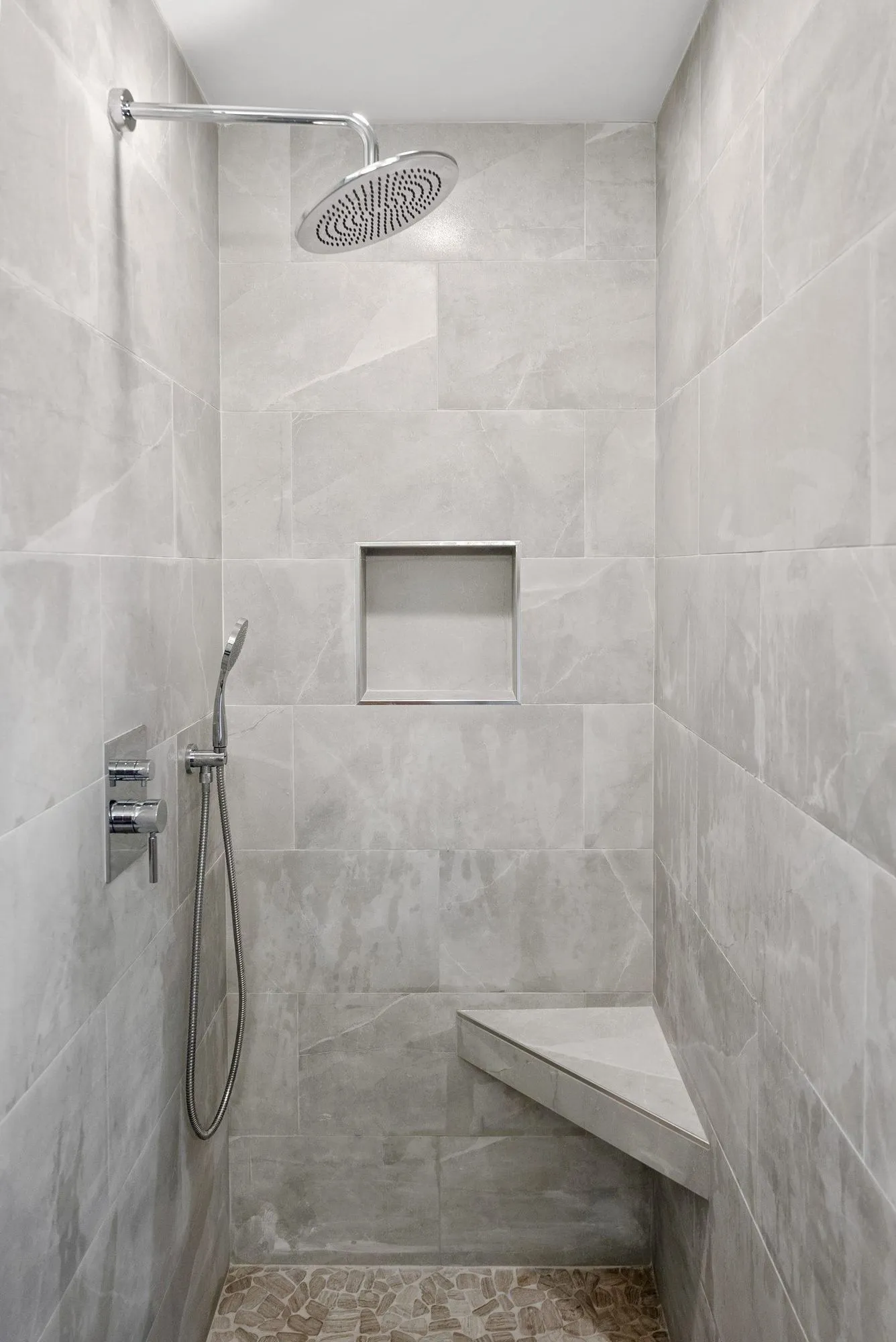 Walk-in shower in large-format stone-look tile with a built-in bench and recessed niche