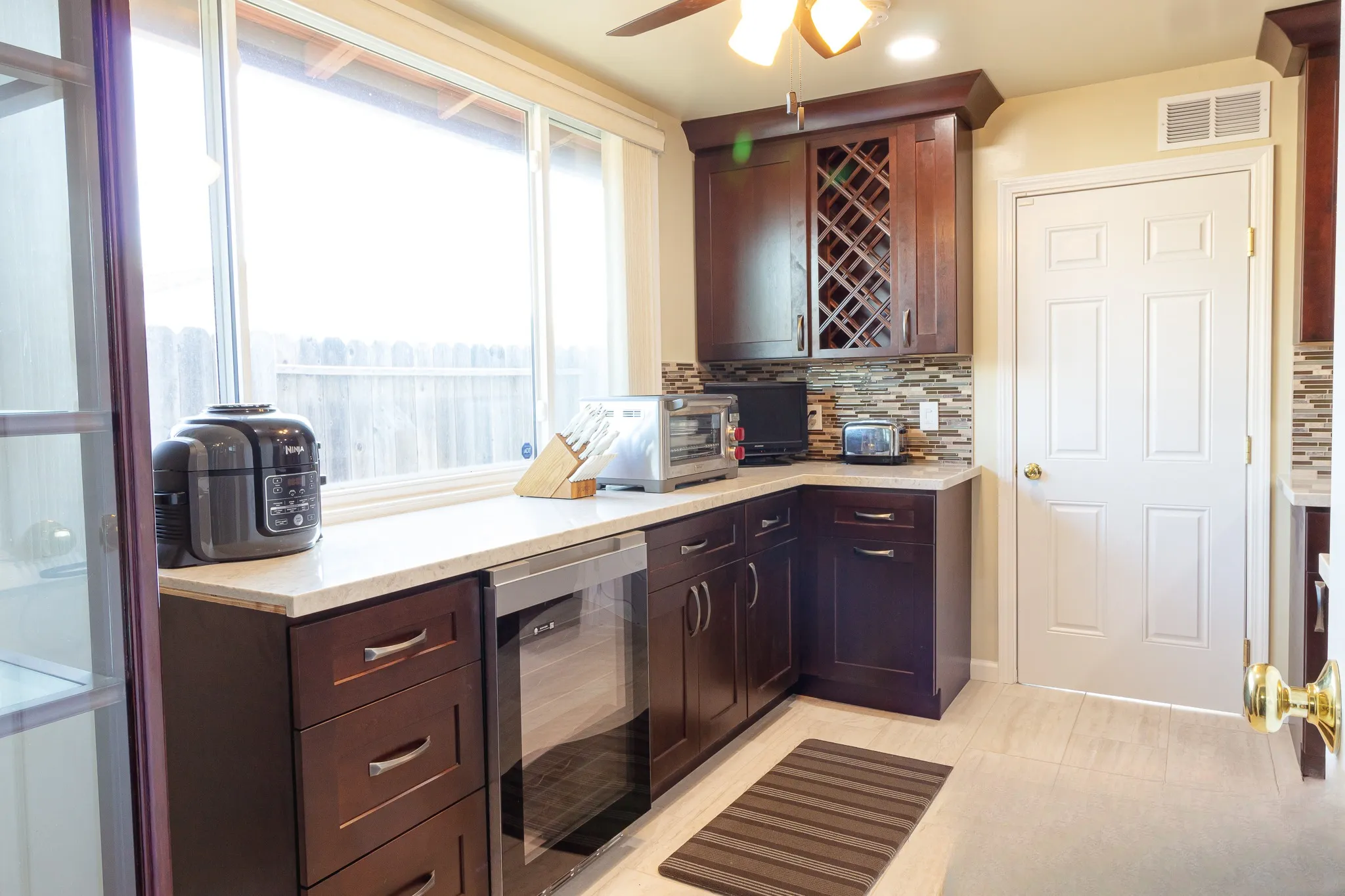 Run of espresso shaker cabinetry with a lattice wine rack cabinet above and a glass-fronted beverage refrigerator below